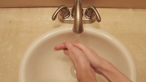 Top-down-shot-of-hands-being-washed-under-a-bathroom-sink