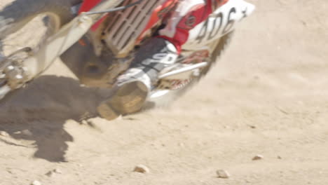 SLOW-MOTION:-A-dirt-biker-rides-his-red-motorcycle-through-the-desert-and-whips-around-a-berm