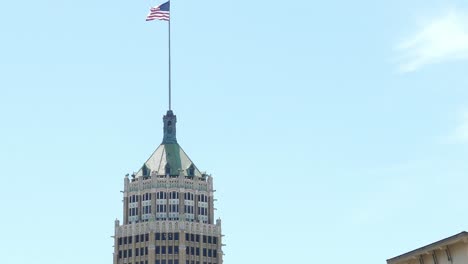 Bandera-Ondeando-Al-Viento-En-La-Parte-Superior-Del-Edificio-Del-Gobierno-De-San-Antonio,-Texas