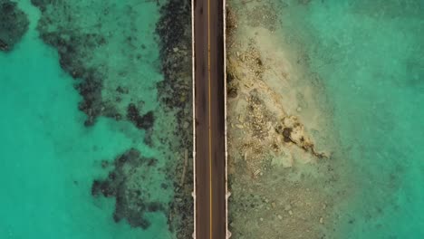 Birds-eye-view-of-car-bridge-over-turquoise-water-on-tropical-island