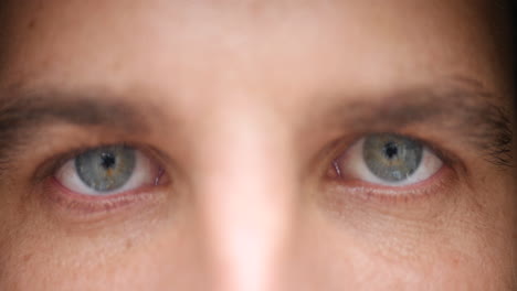 Close-up-of-a-young-man-open-his-light-blue-eyes,-staring-at-the-camera-without-blinking