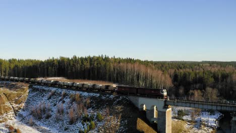 Cargo-train-crossing-bridge-during-winter.-Aerial-view