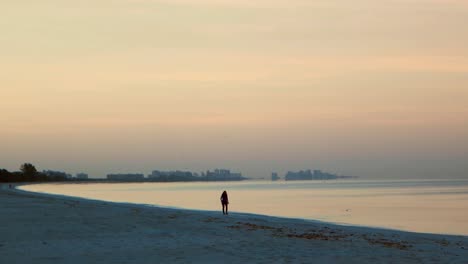 A-female-walking-along-Bonita-Beach,-FL-early-one-morning-just-after-sunrise
