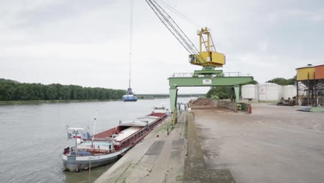 A-yellow-crane-unloads-a-ship-filled-with-fertilizer-at-a-port