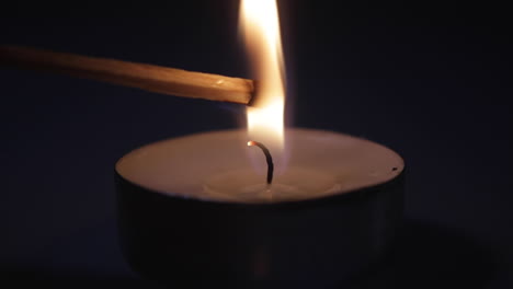 A-close-up-shot-of-a-match-being-put-into-the-flame-of-a-candle-and-exploding-lighting