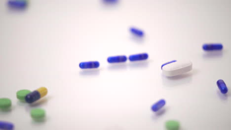 Makro-Von-Pillensorten,-Die-Auf-Eine-Blaue-Und-Gelbe-Pille-Auf-Weißem-Hintergrund-Gleiten