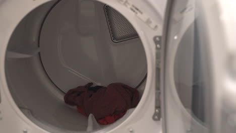 Nahaufnahme-Eines-Mannes,-Der-Kleidung-Aus-Der-Waschmaschine-Daneben-In-Einen-Trockner-Lädt