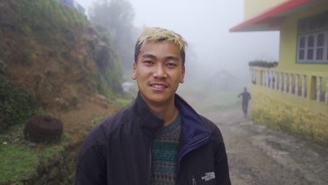 Asian-young-man-with-coloured-blonde-hair-stands-in-misty-or-foggy-morning-smiling