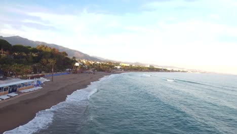 drone-shot-of-marbella-coastline-at-sunset,-summer-vacation-vibes