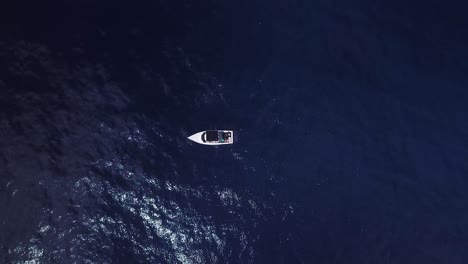 Vogelperspektive-Auf-Ein-Kleines-Weißes-Fischerboot,-Das-Mitten-Im-Tiefblauen-Meer-Liegt,-Ohne-Dass-Andere-Boote-In-Der-Nähe-Sind