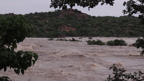 Dorf,-Bäume-Und-Kleine-Hügel,-Die-Aufgrund-Starker-Regenfälle-Von-Überschwemmungen-überschwemmt-Wurden-Und-Einen-Starken-Wasserfluss-Aus-Dem-Stausee-In-Nord-Karnataka,-Indien,-Verursachten