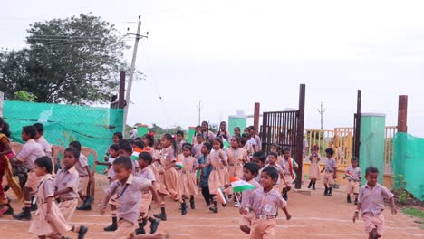 Gruppe-Fröhlich-Lächelnder-Grundschulkinder,-Die-Während-Des-Unabhängigkeitstages-Indiens-Mit-Indischen-Flaggen-In-Der-Hand-Durch-Die-Schule-Laufen