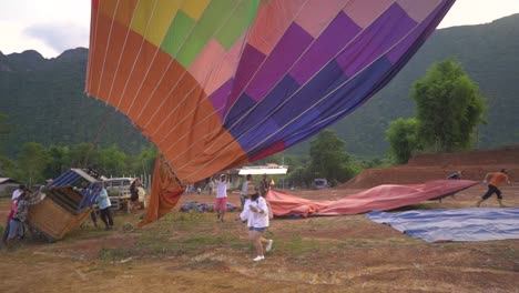 Ein-Heißluftballon-Ist-Gelandet-Und-Der-Ballon-Sinkt-Langsam-Zu-Boden,-Während-Die-Leute-Daran-Arbeiten,-Ihn-In-Die-Richtige-Richtung-Zu-Bringen