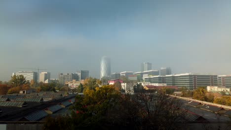 Der-Nebel-Und-Die-Wolken-Geben-Den-Blick-Auf-Die-Bäume-Und-Gebäude-Frei,-Unter-Einem-Blauen-Himmel-Und-Zeitrafferaufnahmen