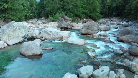 Wide-shot-of-a-man-relaxing-on-a-giant-rock-at-the-Verzasca-valley,-Switzerland