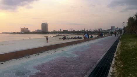 Groups-of-people-enjoying-the-evening-sunset-at-Araha-Beach,-Chatan,-Okinawa,-Japan