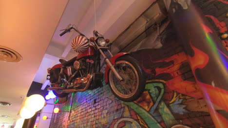 Leitartikel,-Blick-Auf-Das-Innere-Des-Restaurants,-Wunderschönes-Modernes-Dekor-Und-Design,-An-Der-Decke-Hängendes-Motorrad,-Bunte-Graffitiwand-Und-Menschen,-Die-Im-Restaurant-Essen