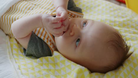 Süßes-Baby-Spielt-Mit-Händen,-Lacht-Und-Macht-Gesichter,-Während-Es-Auf-Dem-Boden-Liegt
