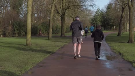 Active-fitness-group-jogging---walking-in-wet-rainy-park-in-slow-motion-rear-view