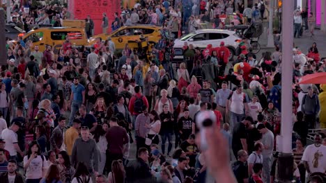 Slow-motion-shot-of-the-crowd-at-Times-Square-at-a-summer-night-with-a-360-degree-camera-in-the-foreground-and-cars-passing-in-the-background-in-Manhattan,-New-York-City,-USA