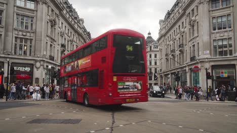 Dos-Pisos-Rojos-Girando-En-Oxford-Street-En-Londres,-Muchos-Autos-Y-Gente-Alrededor