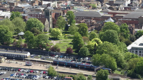 Seguimiento-De-La-Vista-Aérea-De-Un-Tren-De-Cercanías-Que-Sale-De-La-Estación-Este-De-Maidstone-Y-Cruza-El-Río-Medway-En-Maidstone,-Kent