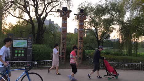 People-pass-by-totem-poles-at-Hosu-park,-Janghang-dong,-Ilsan-gu,-Goyang-si,-Gyeonggi-do,-South-Korea