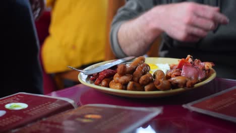 Pork-Sausage-and-Meat-platter-has-been-served-in-a-restaurant-in-a-yellow-plate-with-knife-and-a-fork