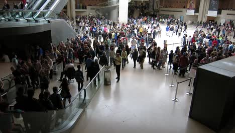 Medium-shot-over-a-large-indoor-square-of-the-Louvre-museum-full-of-visitors,-Paris,-France