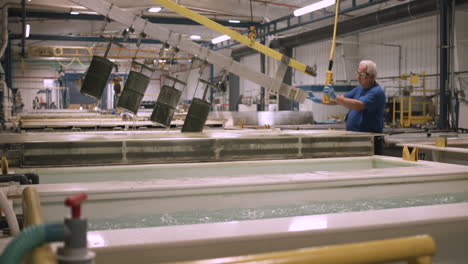 American-laborer-uses-a-gantry-crane-to-place-metals-in-a-chemical-bath-inside-a-manufacturing-plant-stabilized-slider-shot