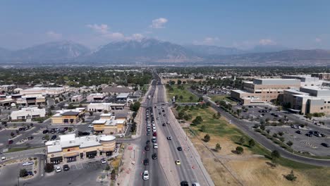 Cars-Driving-On-The-Asphalt-Road-In-Riverton,-Utah-With-View-Of-Riverton-Hospital-Building-On-A-Sunny-Day---static-drone-shot