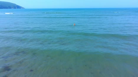 Aerial-pan-over-little-girl-jumping-the-waves-in-the-sea