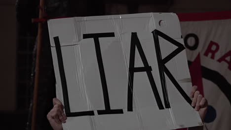 A-protestor-holds-a-white-placard-up-that-says-“Liar”-in-black-writing-on-a-protest-against-Prime-Minister-Boris-Johnson