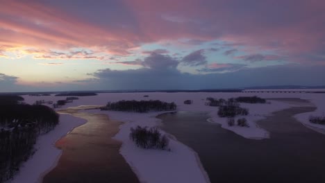 Stunning-sunset-making-clouds-purple-viewed-by-flying-drone-in-winter-scenery
