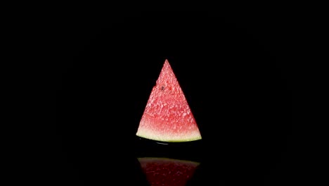 Nahaufnahme-Einer-Halben-Wassermelone,-Die-Sich-Auf-Der-Schwarzen-Wasseroberfläche-Dreht