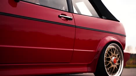 Red-modified-VW-Volkswagen-Golf-MK1-car-driving-slowly-with-gold-BBS-wheels,-medium-shot