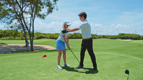 Cámara-Lenta:-Instructora-De-Golf-Enseñando-La-Postura-Del-Golf-A-Una-Estudiante-Y-El-Manejo-Correcto-Del-Club-En-El-Campo-Verde