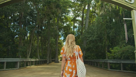Rückaufnahme-In-Zeitlupe-Eines-Schönen-Blonden-Mädchens-Mit-Farbenfrohem-Orangefarbenem-Kleid,-Das-Zu-Florida-Springs-Aufwacht