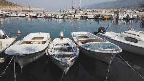 Small-fishing-boats-lined-up-neatly-in-calm-Croatian-marina-on-a-sunny-day