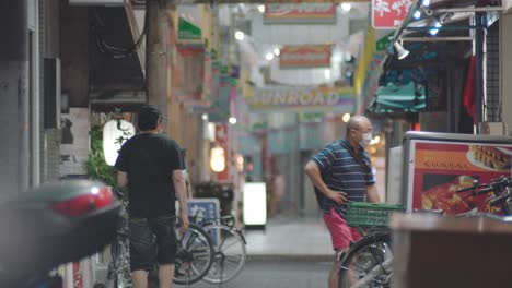 Most-Shops-Are-Closed-Due-To-COVID-19-At-The-Street-Of-Tokyo-In-Kamata,-Oto-City-At-Night---Couple-Wearing-Face-Masks-And-Entering-A-Japanese-Restaurant-To-Eat-Dinner