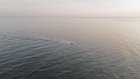 Tilting-down-on-a-boat-motoring-across-the-sea-during-a-winter-sunrise-off-the-coast-of-Maine-AERIAL