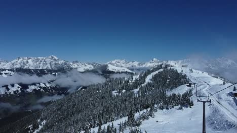 Verschneites-Skigebiet-Mit-Pinien,-Wolken-In-Den-Tälern