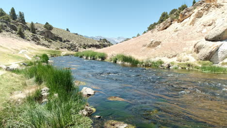 Río-Que-Fluye-A-Través-Del-Bosque-Nacional-Inyo-En-El-Sitio-Geológico-De-Hot-Creek,-Cielo-Azul-Y-Sol