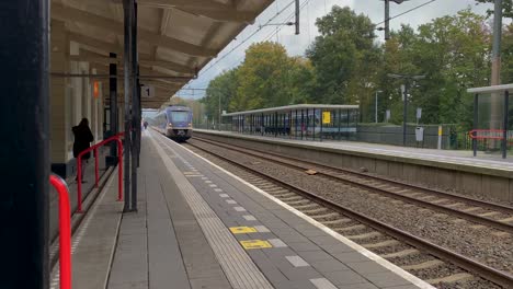 An-electric-train-approaches-the-platform-and-passengers-board-the-carriages-of-a-small-town