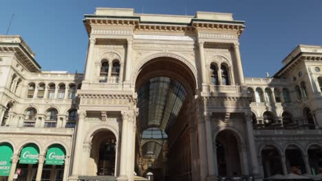 Galleria-Vittorio-Emanuele-II-main-triumphal-arch-entrance-from-the-Piazza-Duomo,-wide-orbit-shot-during-bright-sunny-day