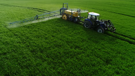 Drone-shot-of-tractor-spraying-pesticides-on-green-field-with-sprayer-at-spring