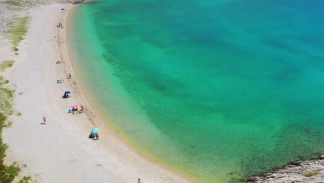 Aerial-forward-above-tourists,-pristine-sea-water,-Pag-Island,-Croatia