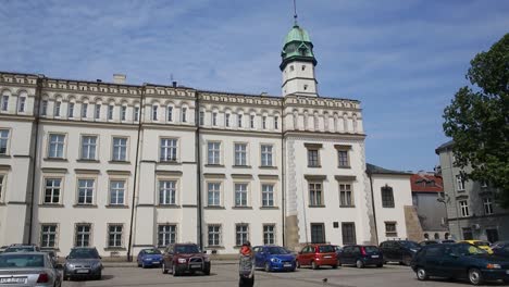 Woman-with-covered-face-on-Wolnica-Market-Square-in-Krakow,-walks-by-Town-Hall