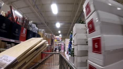 Retail-shopping-cart-moving-down-Christmas-decorations-aisle-in-shopping-mall-during-covid-pandemic