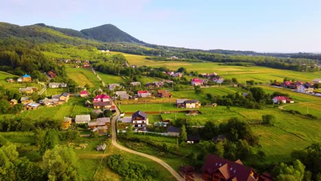 Aerial-view-overlooking-a-idyllic-town-and-lush-green-nature,-in-the-Carpathian-Mountains,-sunny,-summer-day,-in-Ukraine---orbit,-drone-shot